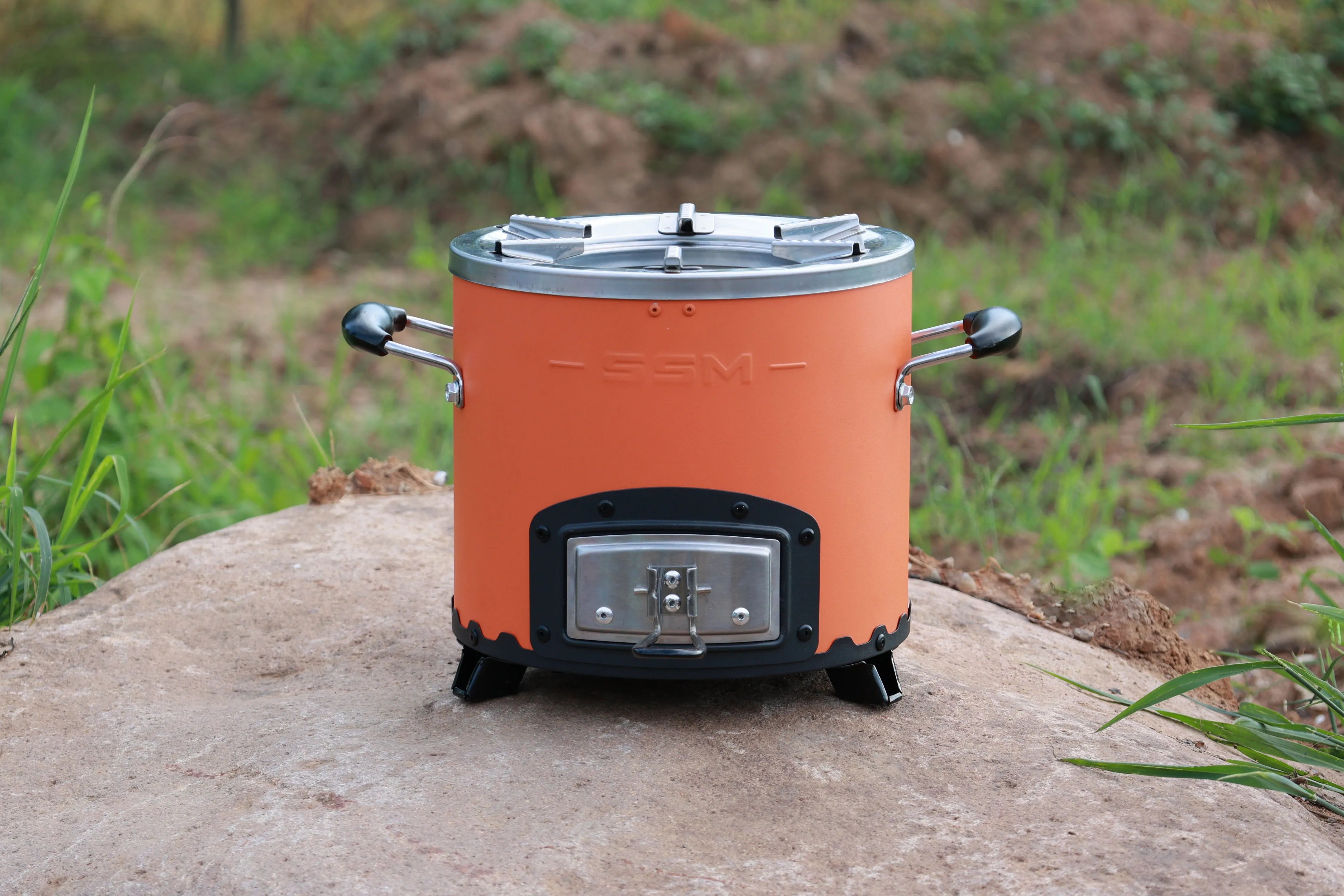 An orange SSM charcoal stove placed on a modern kitchen countertop, surrounded by elegant cookware.