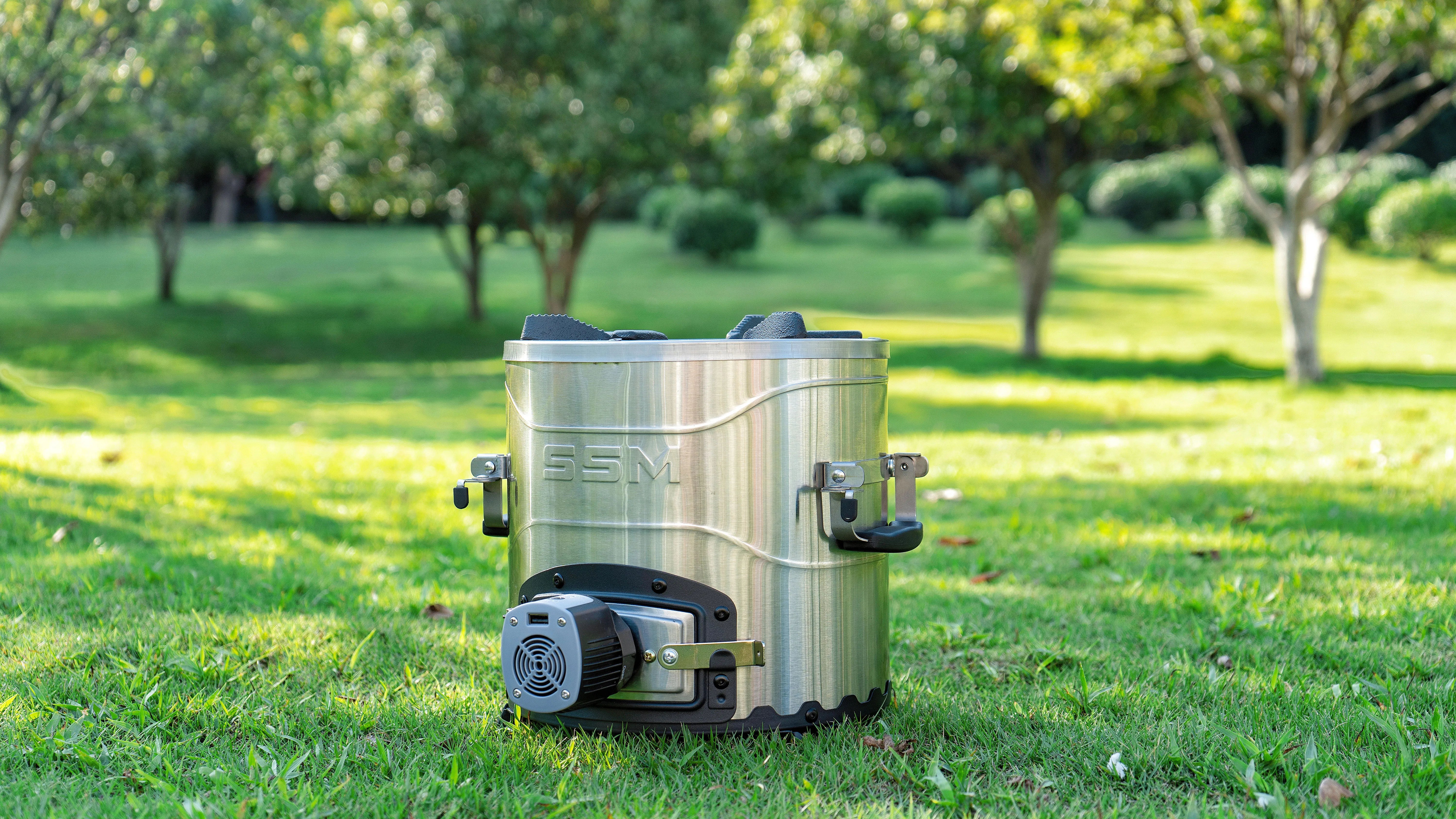 SSM brand portable biomass pellet burning cookstove set up in an outdoor backyard or garden setting.