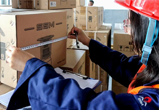 A warehouse inspector measuring an SSM stove product box to ensure accurate and secure shipping and delivery.