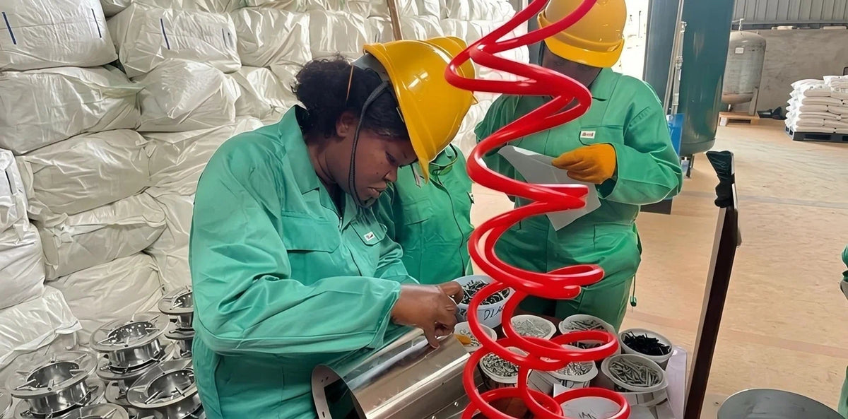 An all-female assembly line team meticulously assembling clean cookstoves using quality components in the Aru Region factory.