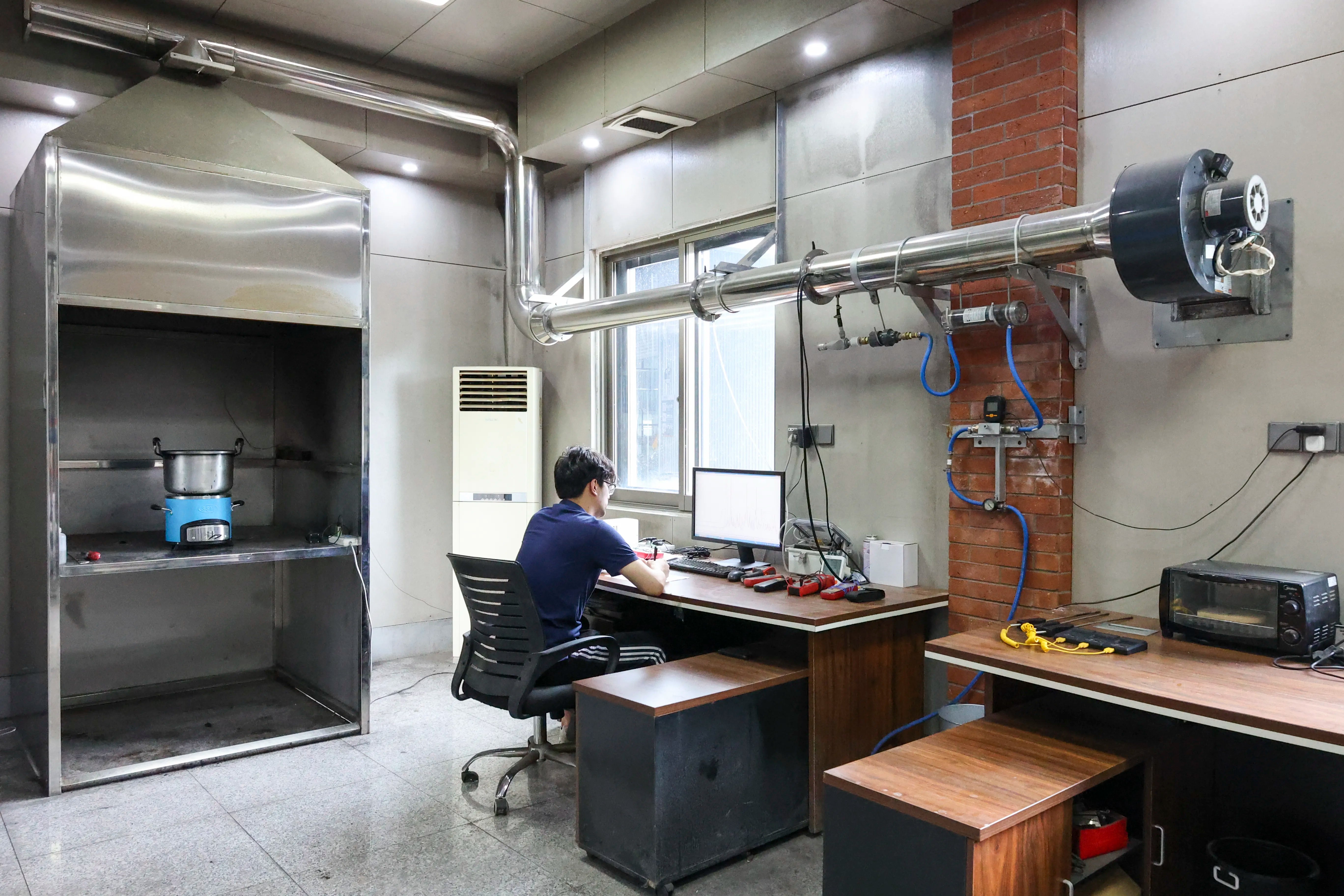An SSM researcher conducting product performance tests at a workstation with advanced laboratory testing equipment and exhaust systems.